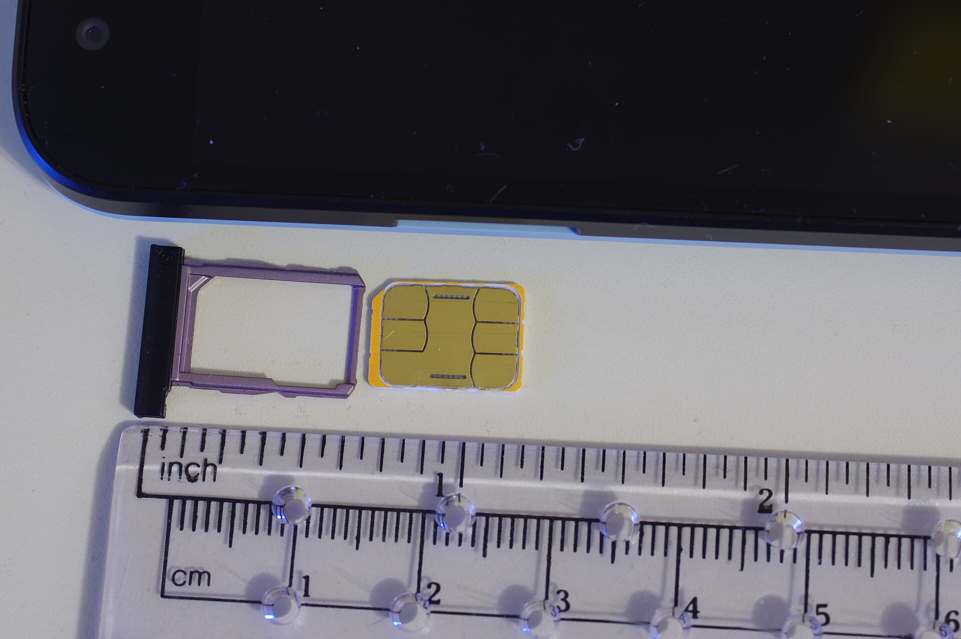 A nano SIM card beside a smartphone SIM tray